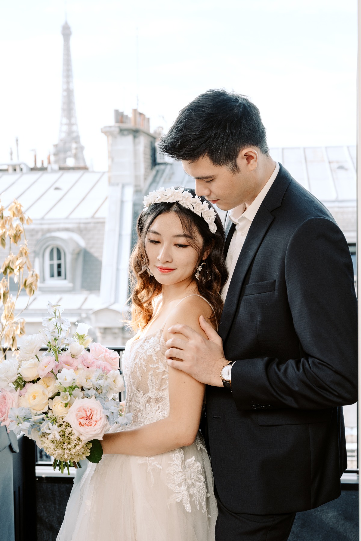 bride and groom pose on balcony with Eiffel tower in the background