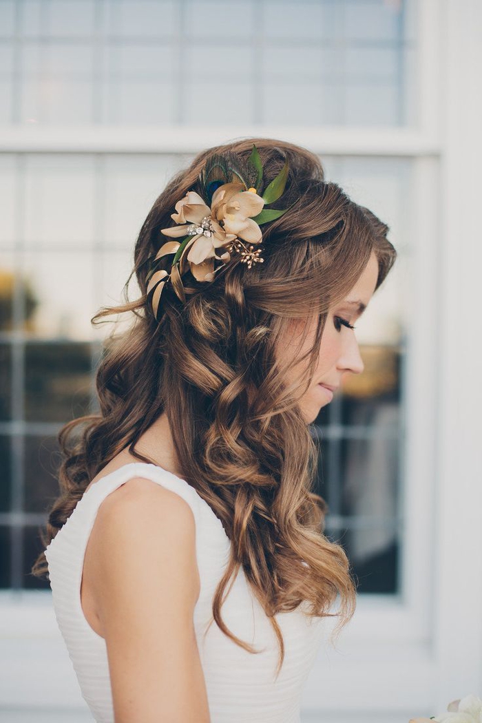 curly hair, a flower in the hair with the green leaves innocent Look, wedding hairstyles