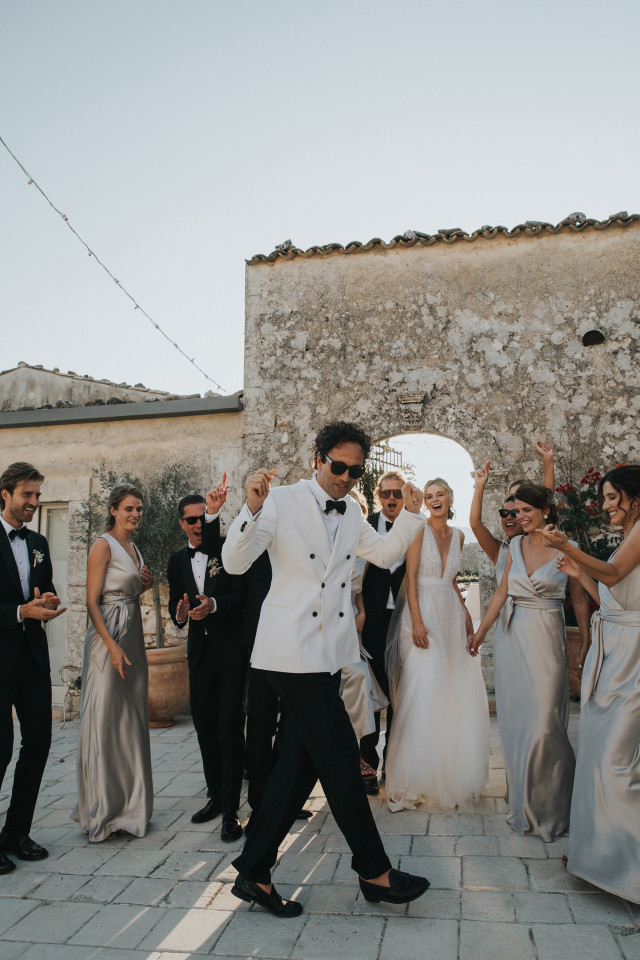 Groom with sunglasses dancing and surrounded by Groomsmen