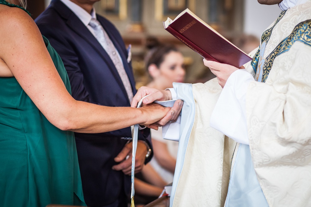 Parish priest places the stole the hands of a couple