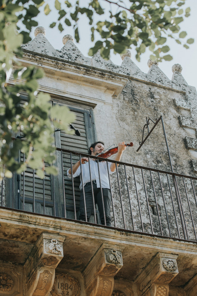 Man on a balcony with a violin