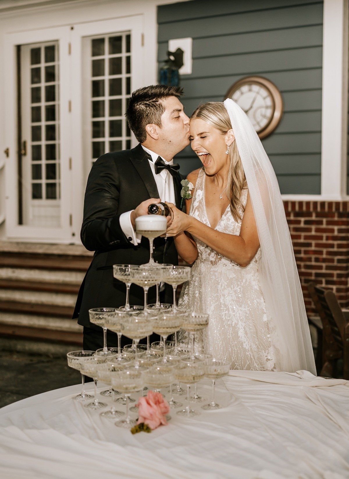 Groom kissing bride at champagne tower