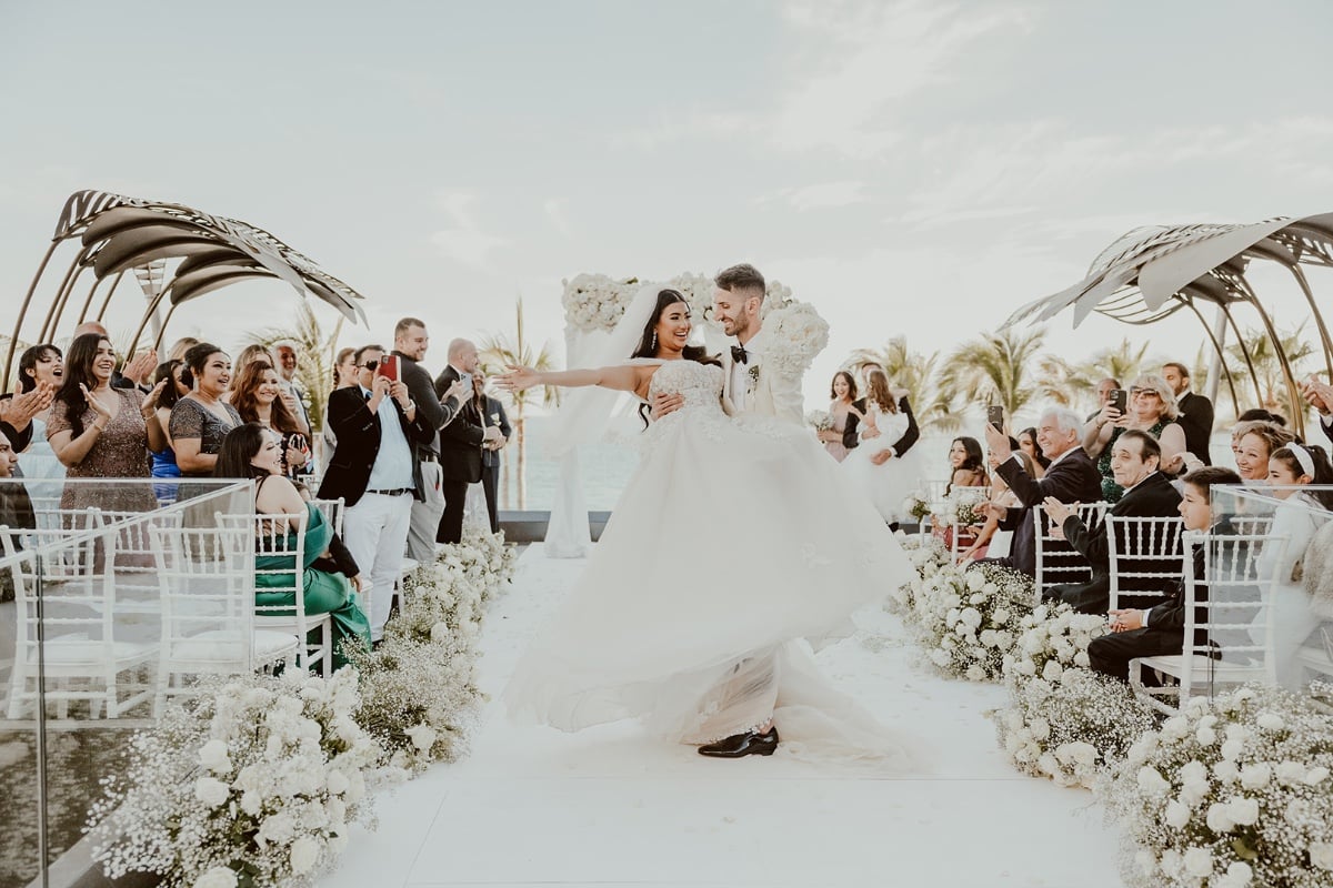 Classic groom carrying bride down the aisle 