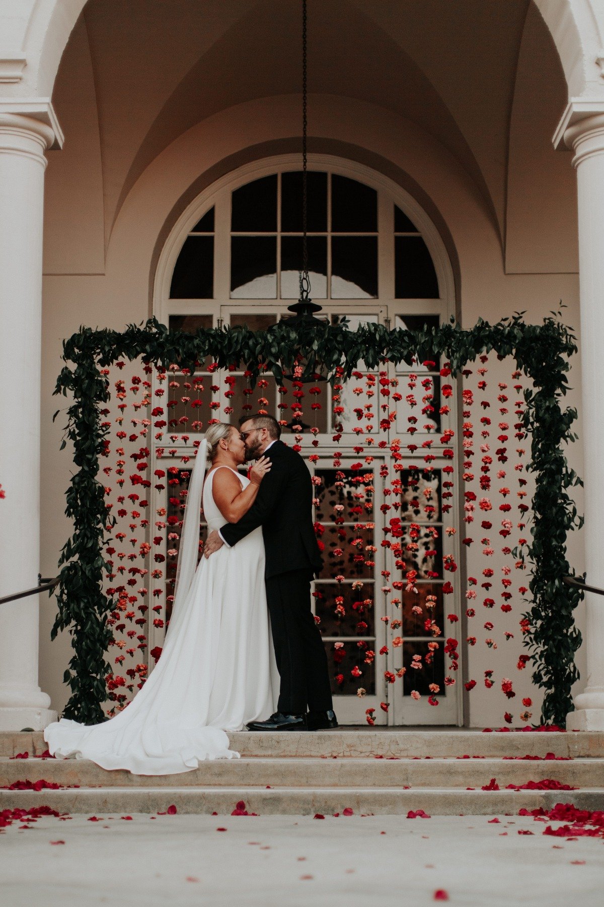 First kiss in front of carnation wall 