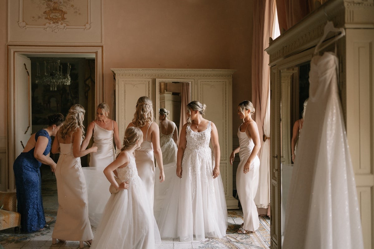 Bridesmaids helping dress the bride 