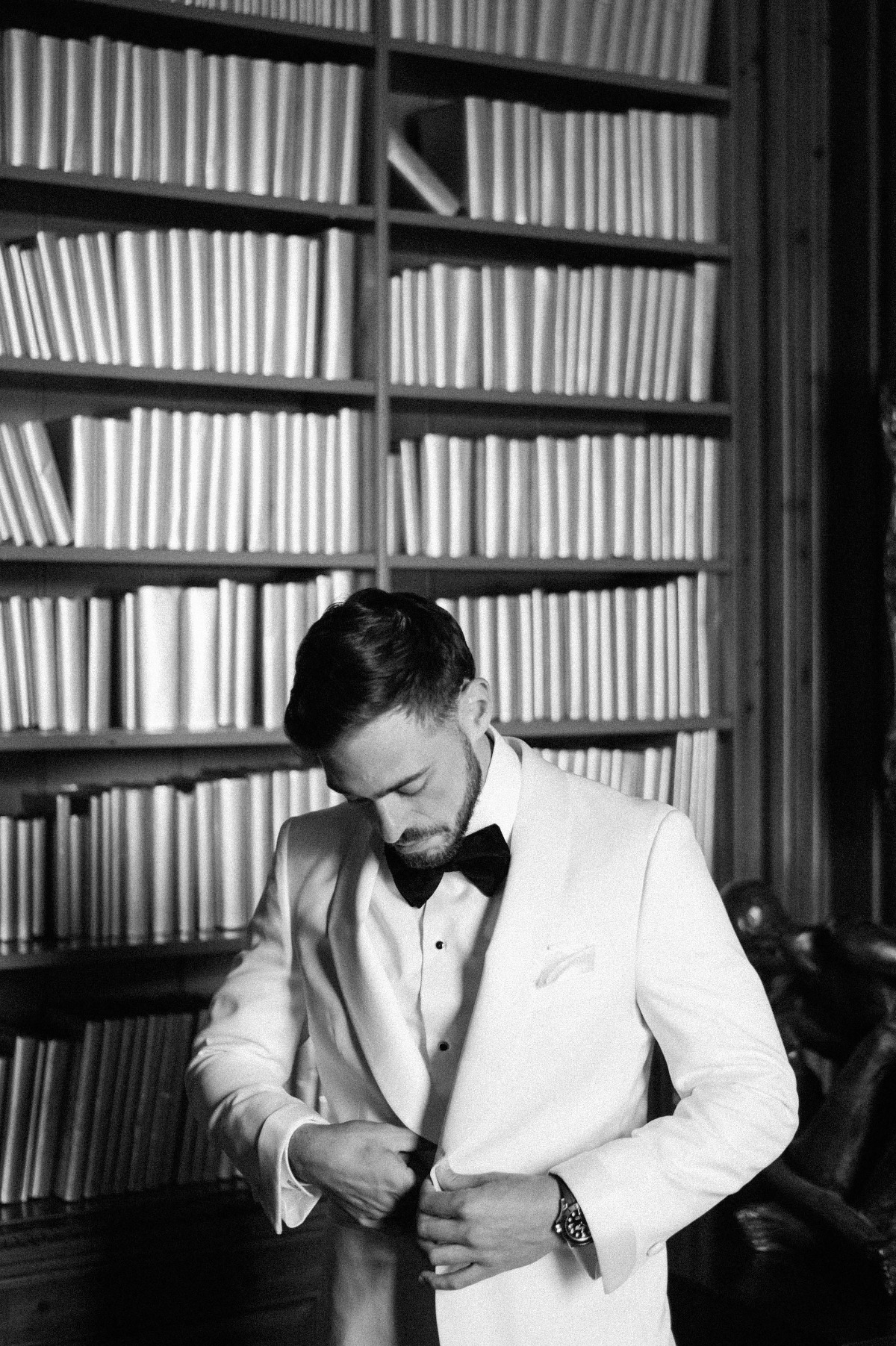 Groom in white vintage suit jacket and black bow tie 