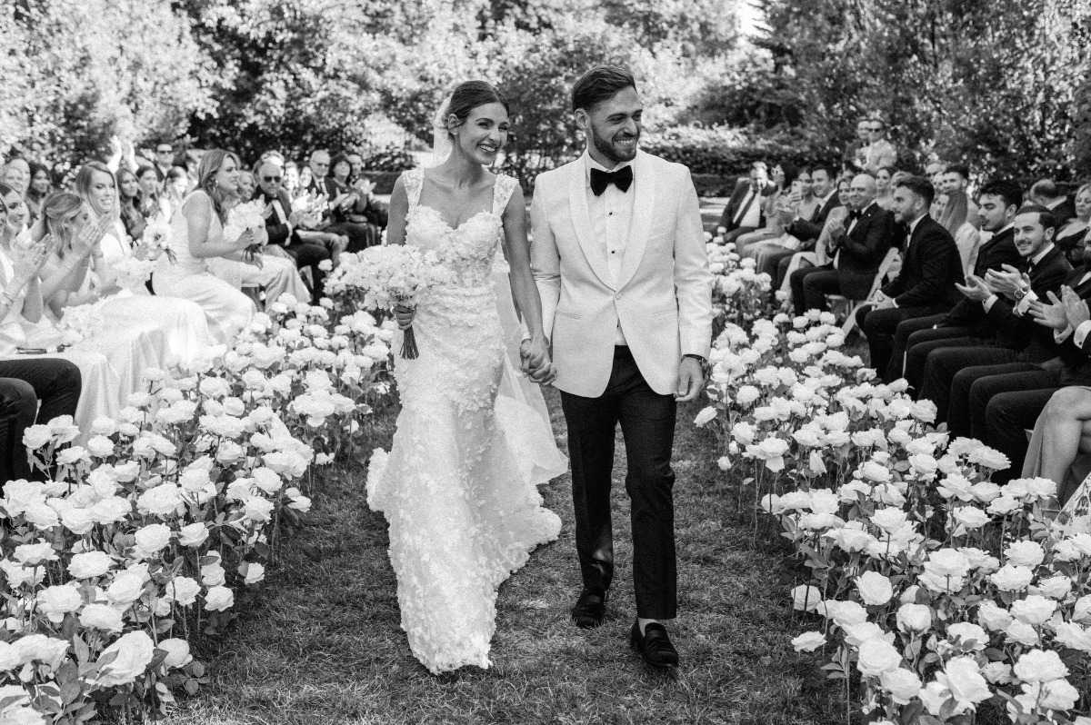 Newlyweds exiting garden wedding reception 