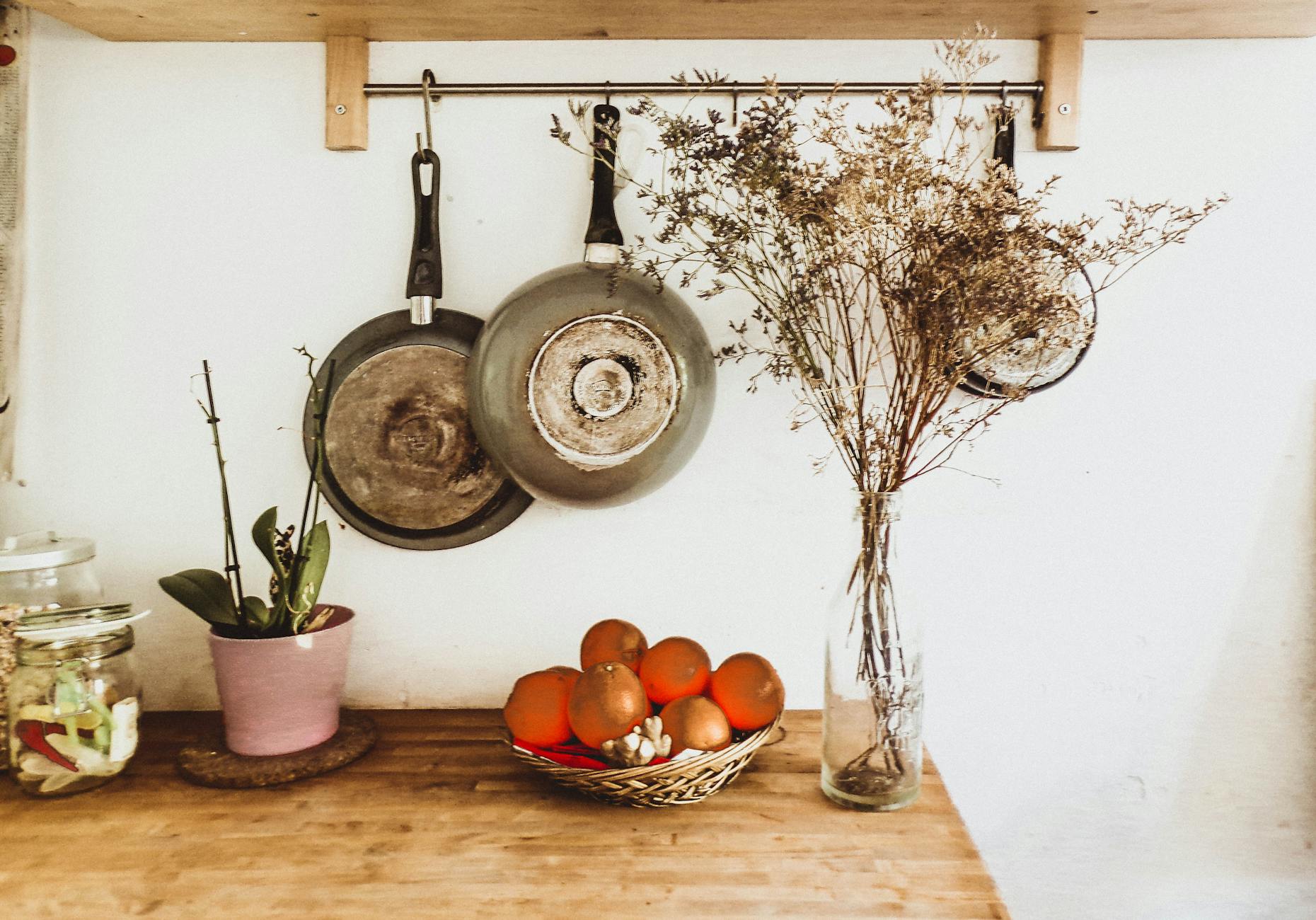 two gray frying pans hanging on wall