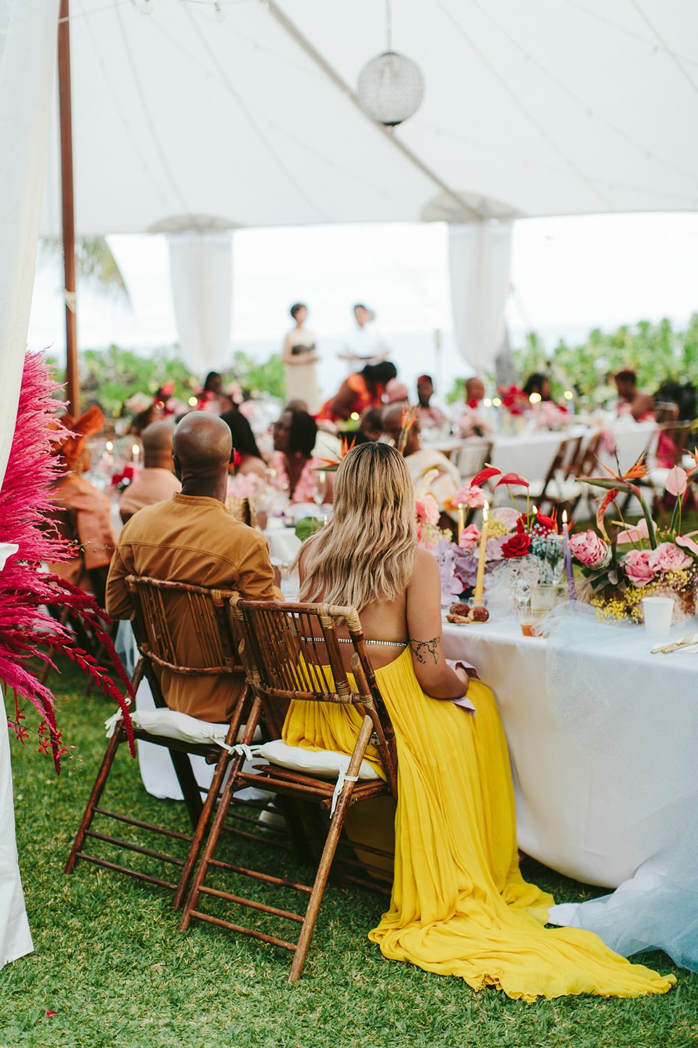 couple enjoying their tented reception in their yellow outfits