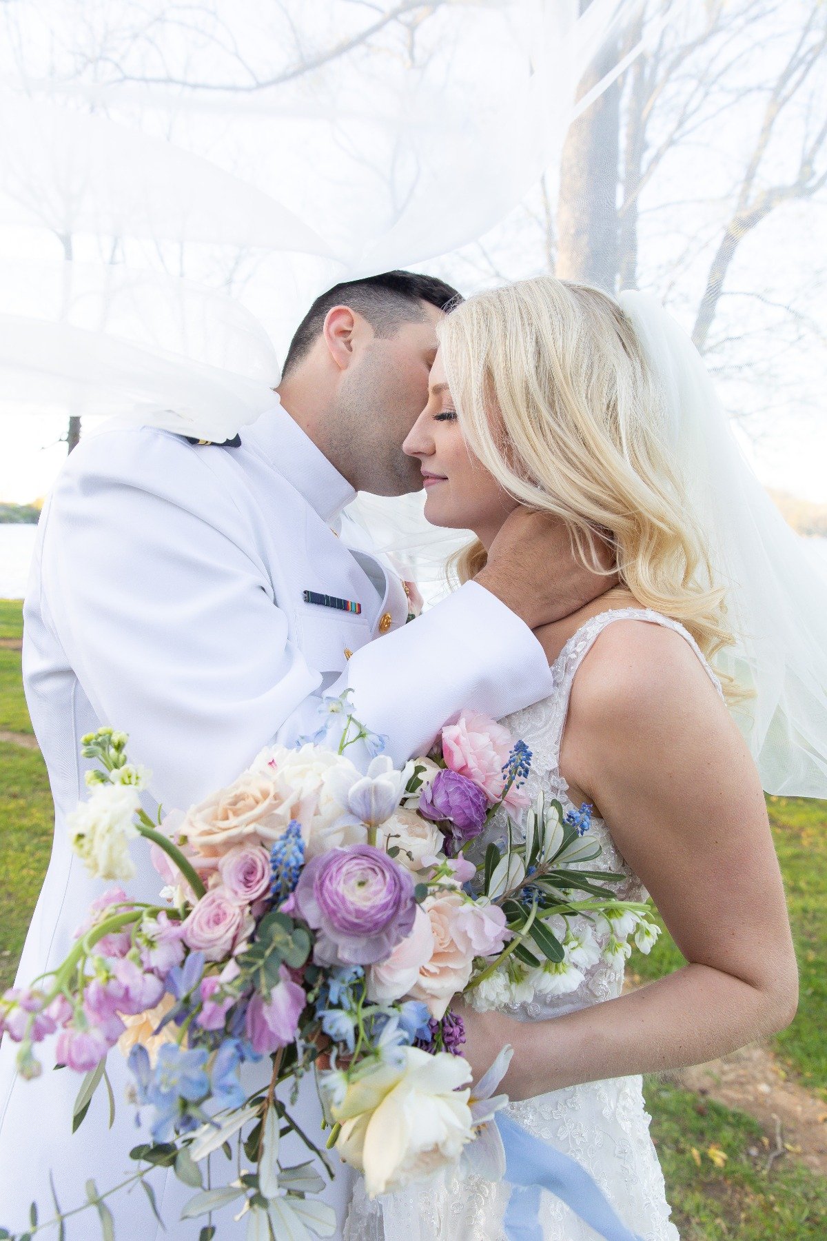 bride and groom in navy uniform with lavender bouquet