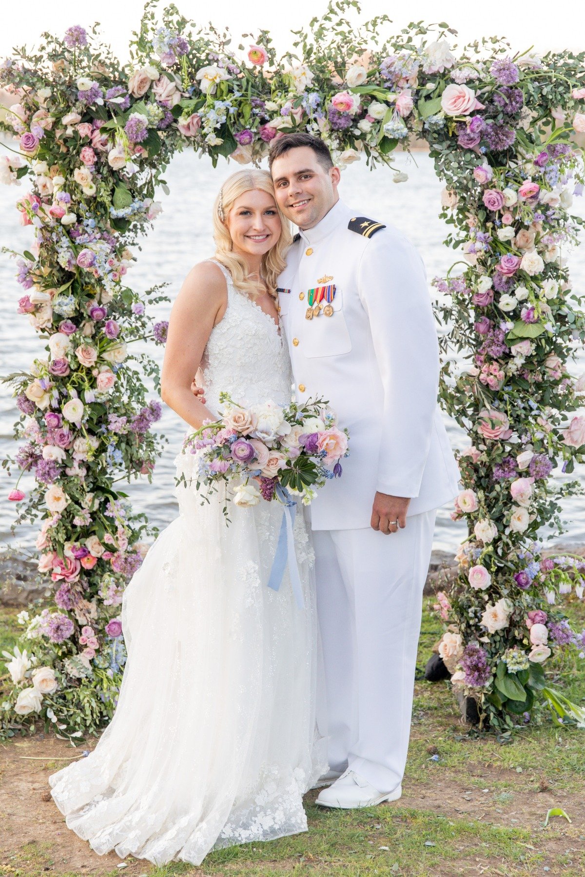 bride and groom at lakefront wedding ceremony with floral arch