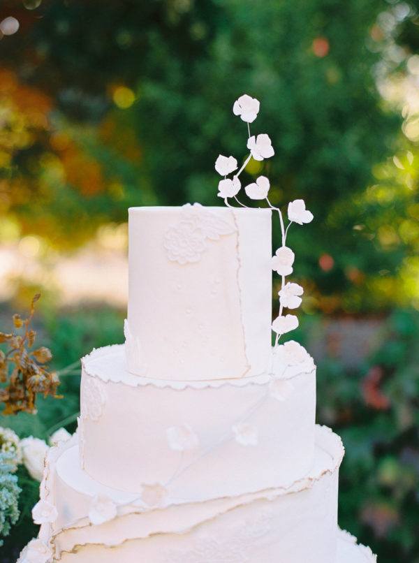 white tiered wedding cake with deckled edging and floating florals