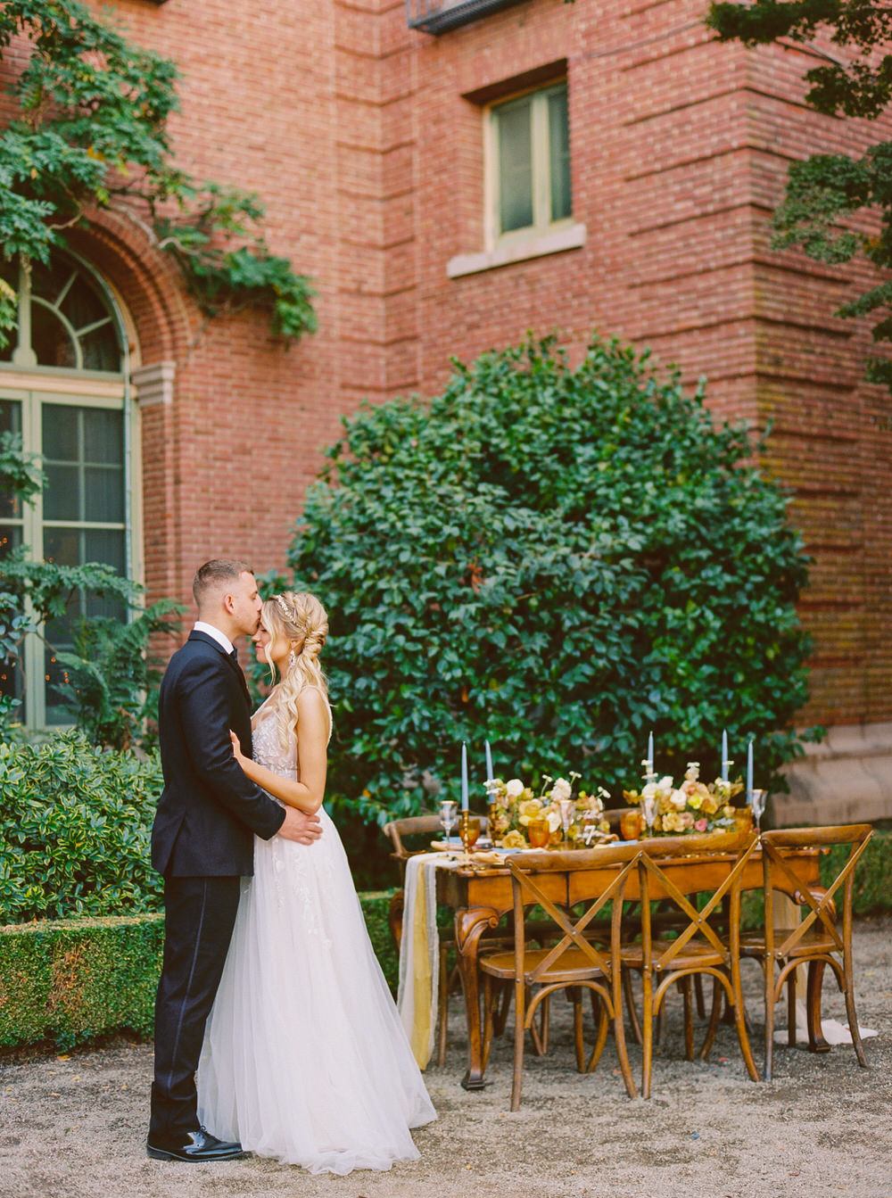 groom kisses his bride's head at their intimate reception in California