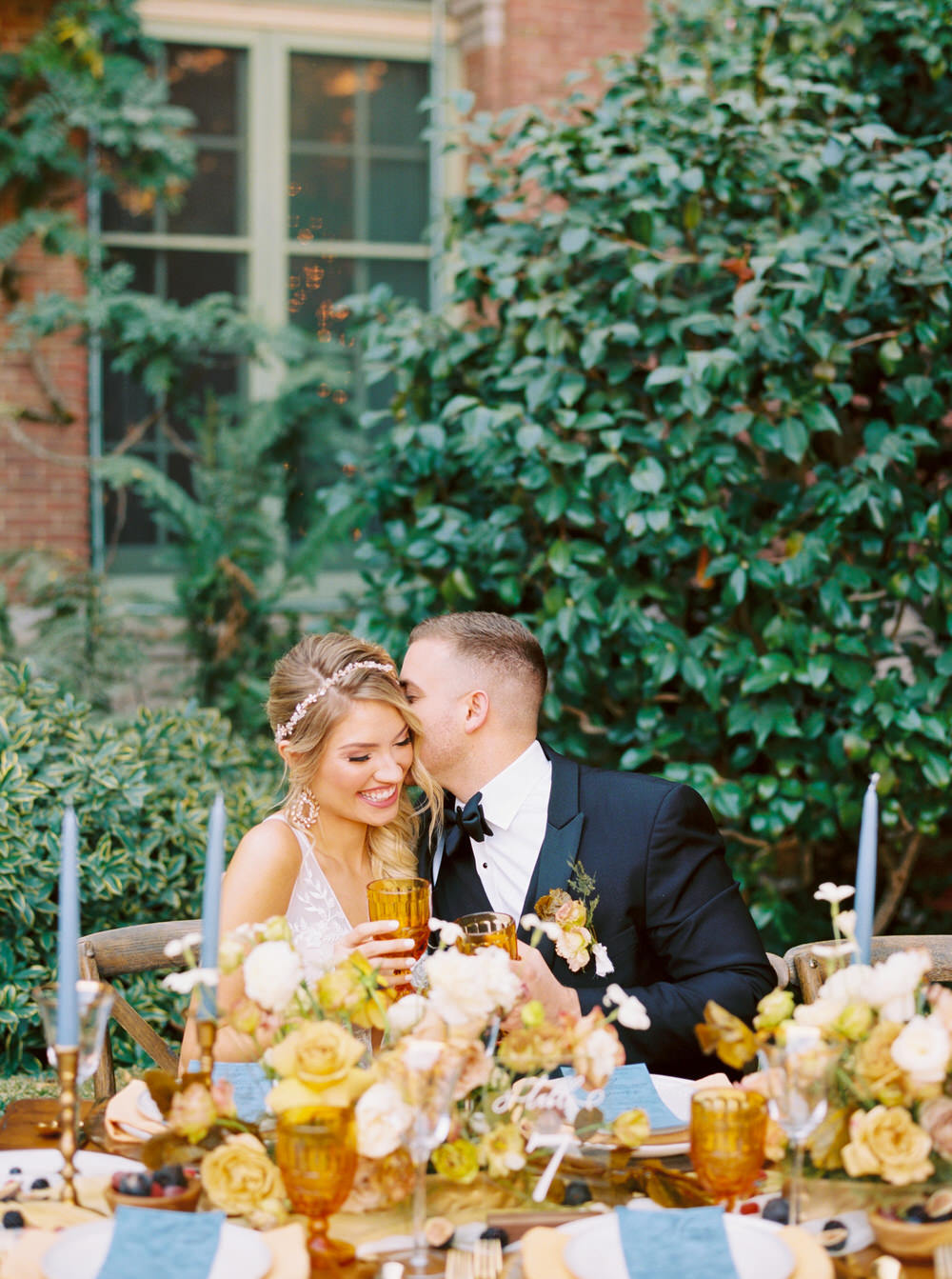 groom kisses his bride on the check during their reception