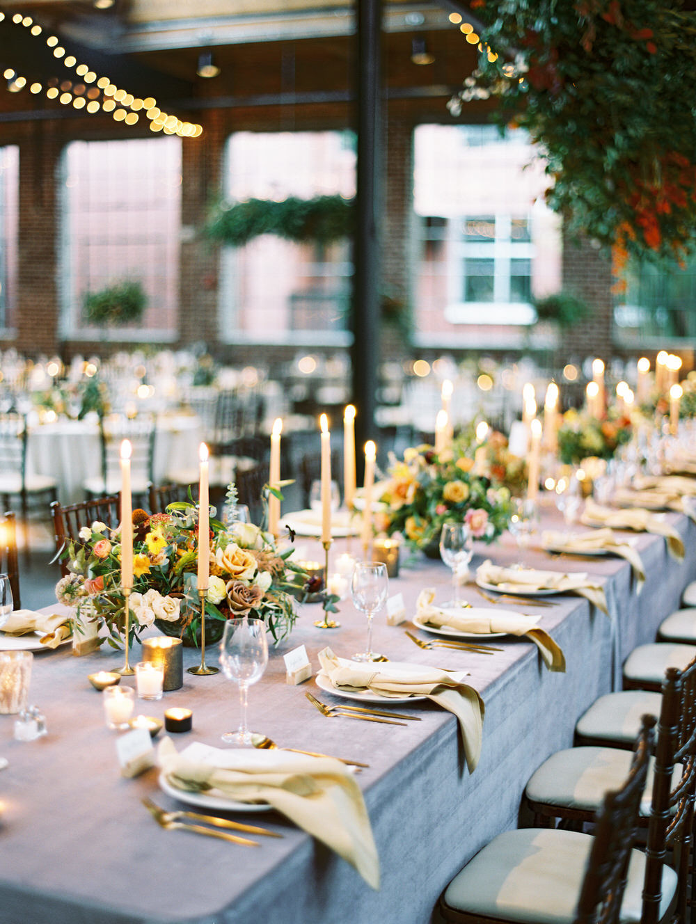 long head table with taper candles and colorful floral centerpieces