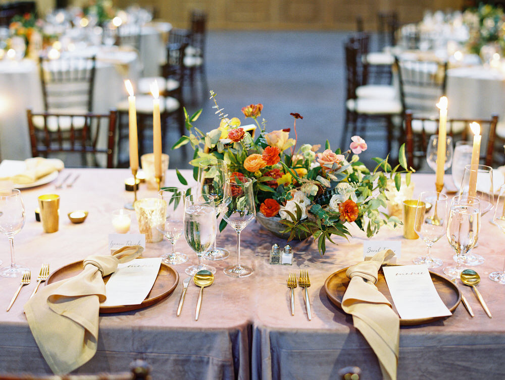 long head table with taper candles and colorful floral centerpieces