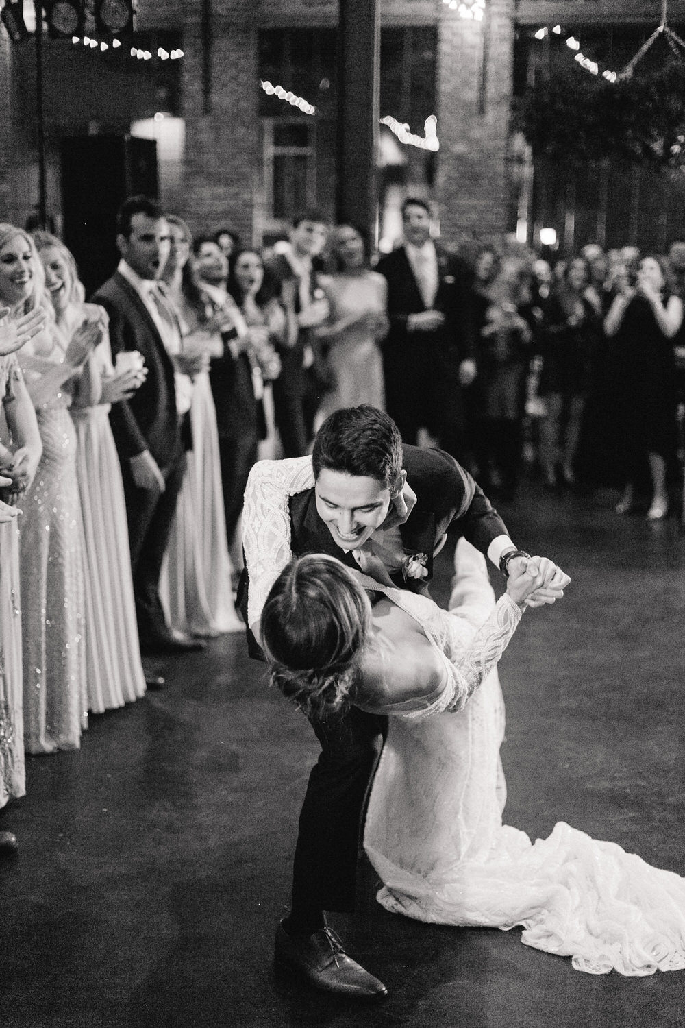 the groom dips his bride during their first dance