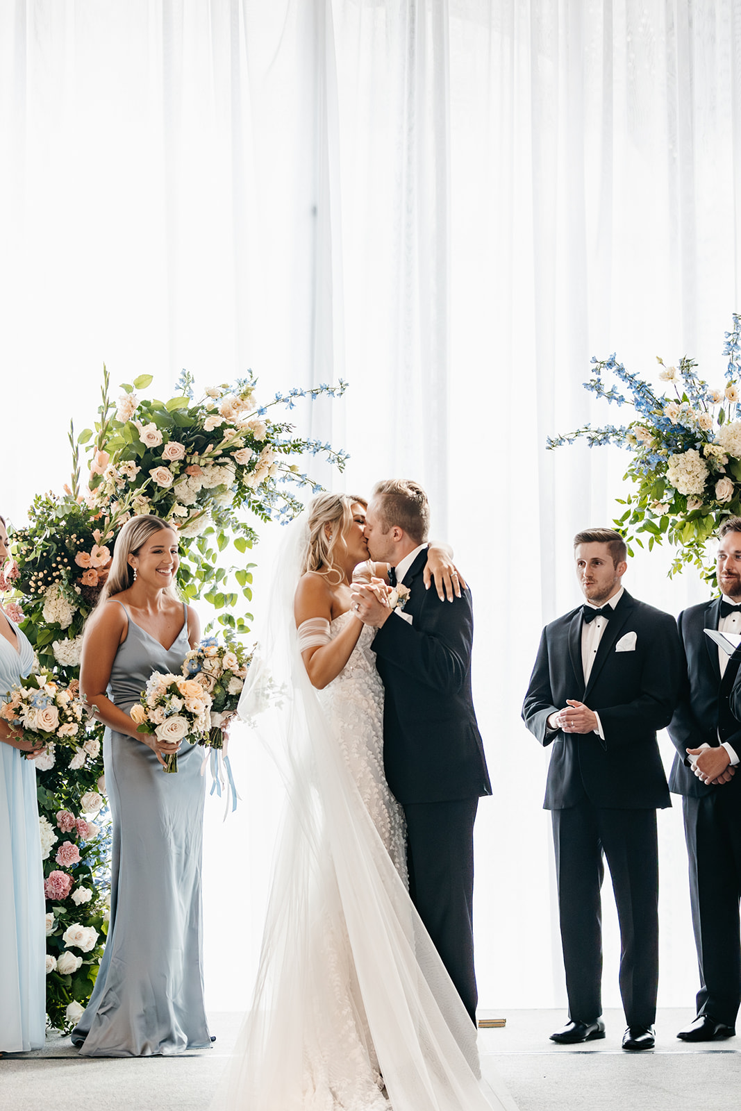 bride and groom kiss at indoor peach and white ceremony