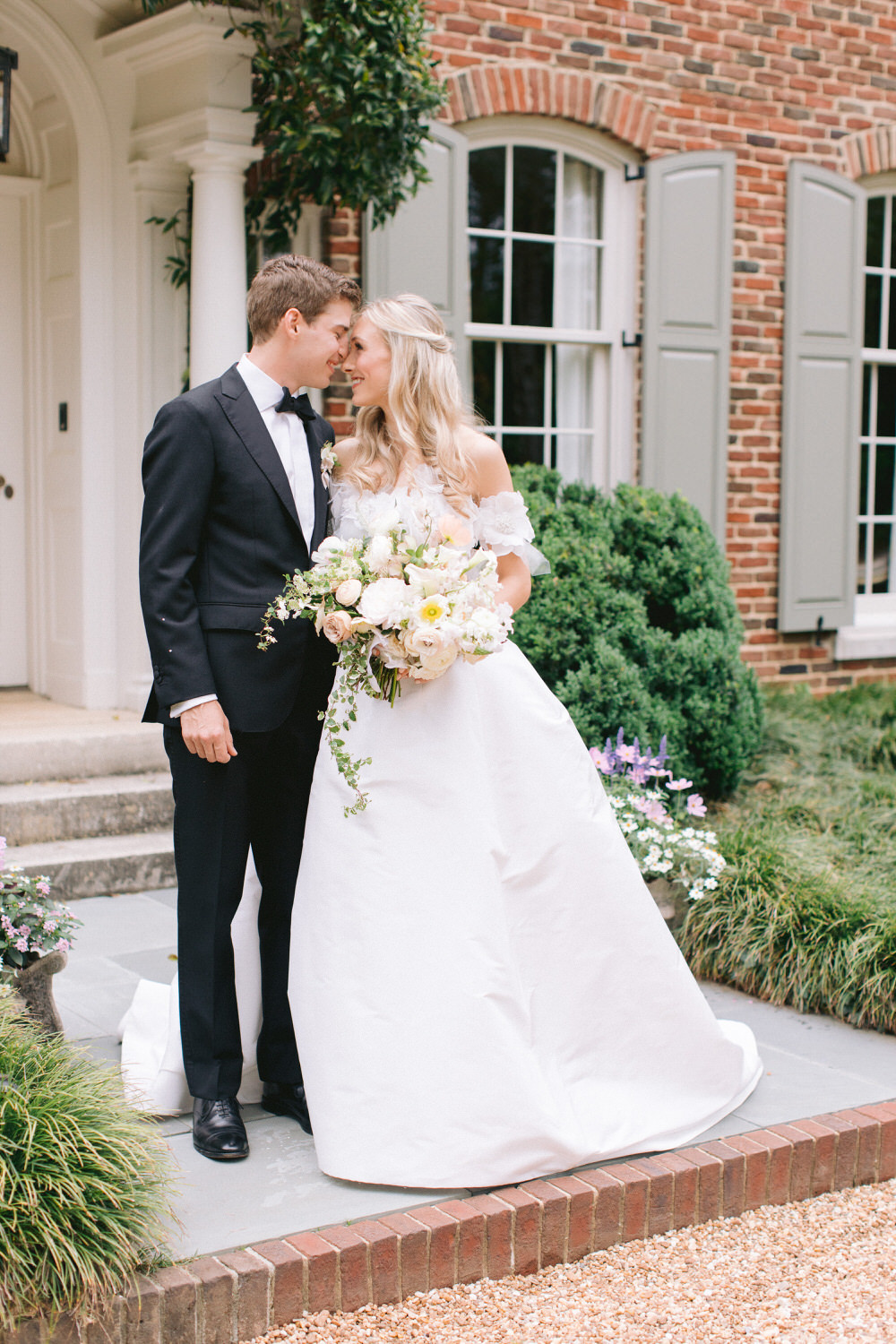 bride and groom kiss in front of a southern brick home