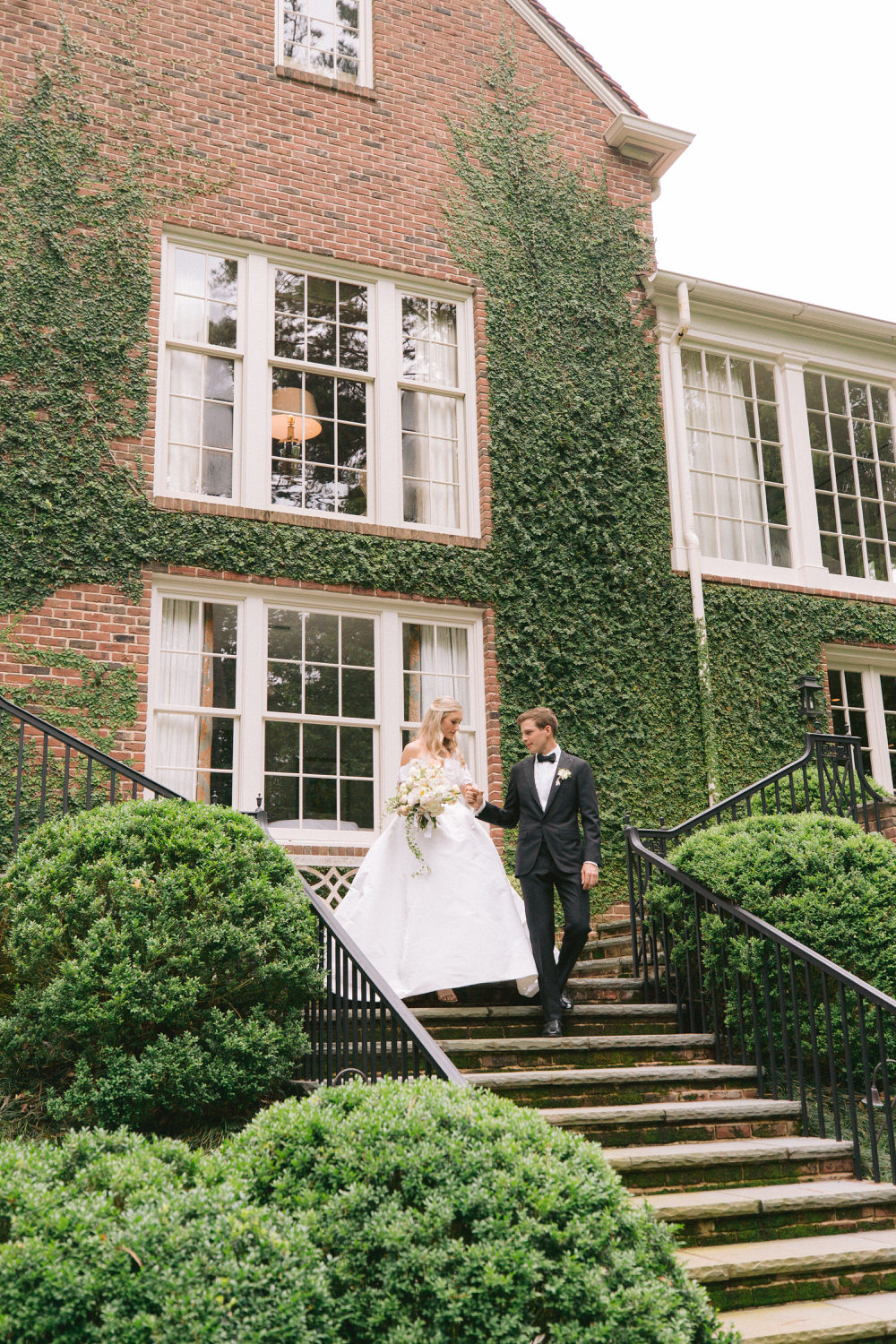 groom helps his bride down the stairs