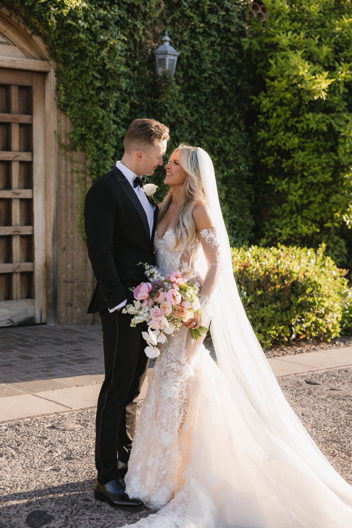 bride and groom pose in front of ivy covered villa 