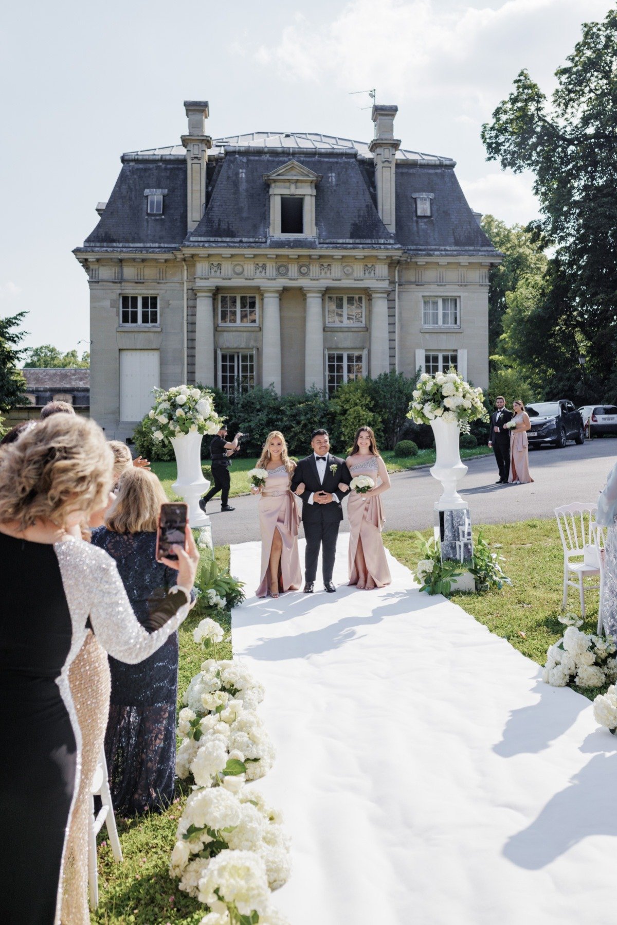 groomsman walks two bridesmaids down the aisle