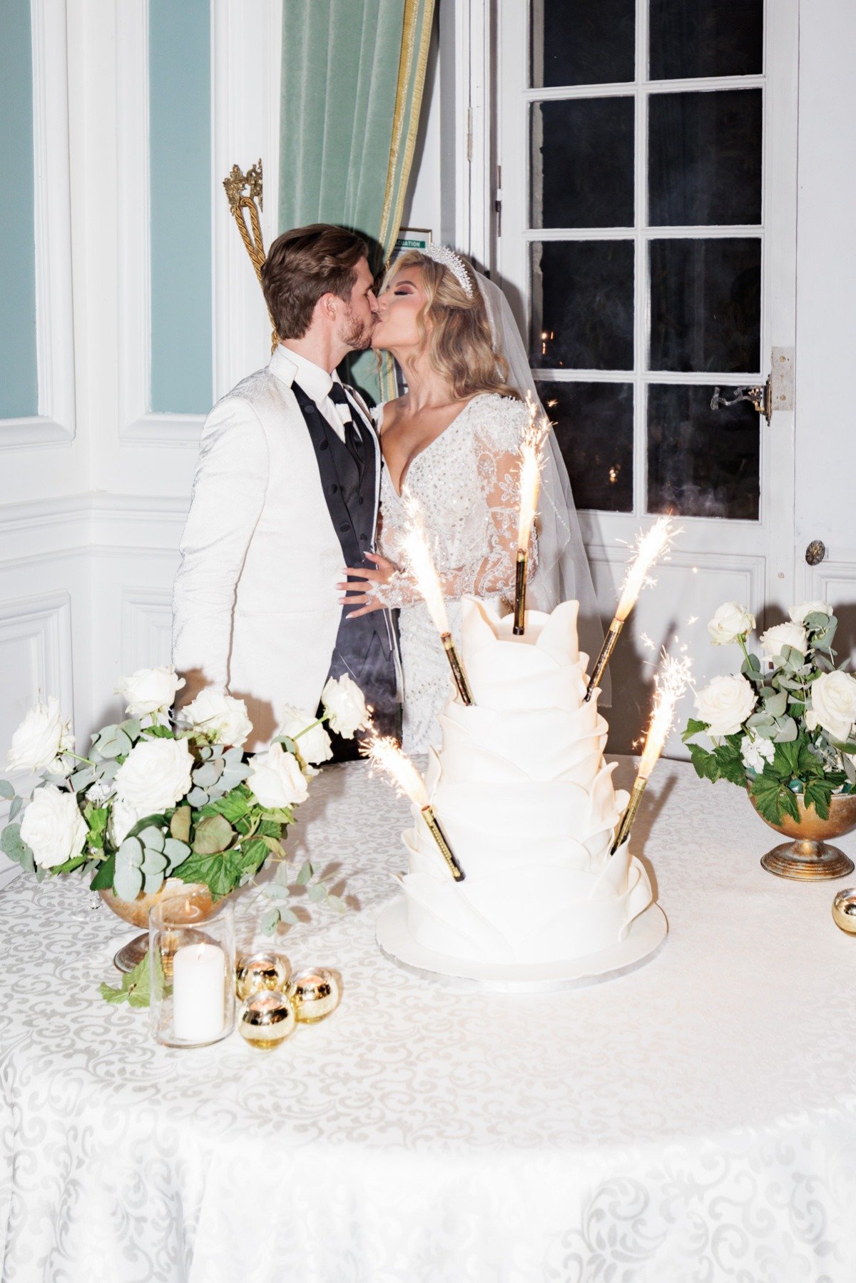 bride and groom with large wedding cake and sparklers