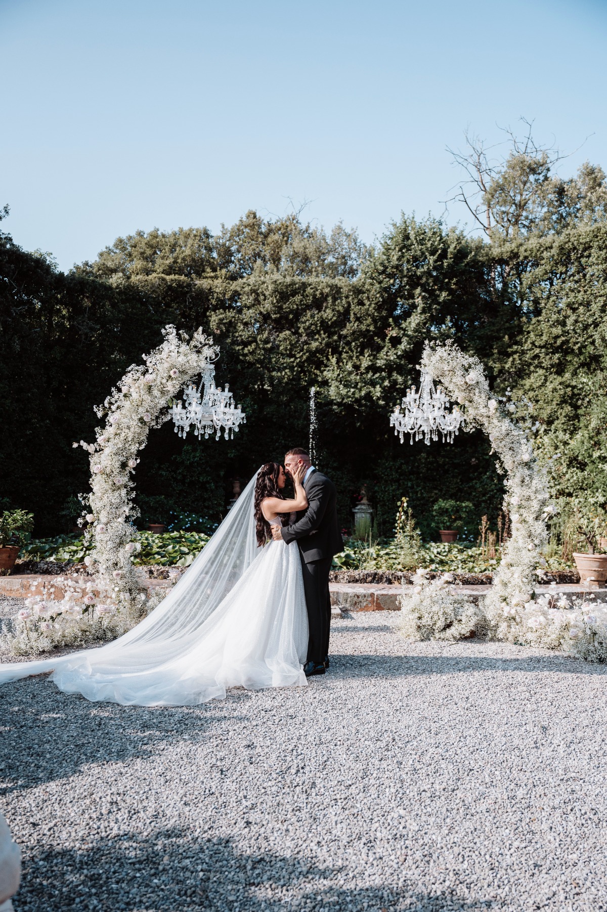 white flower arch with chandeliers for wedding ceremony