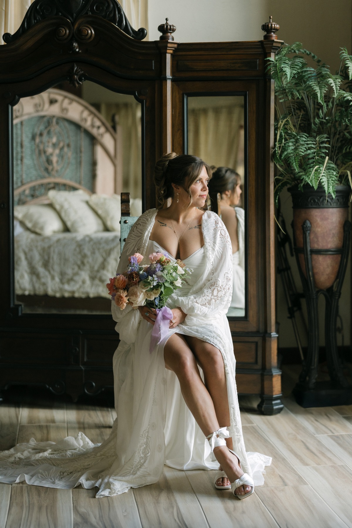 bride sitting in robe in suite looking out window
