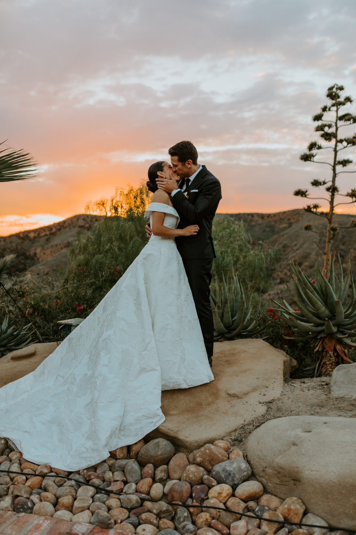 wedding couple kissing with sunset in background